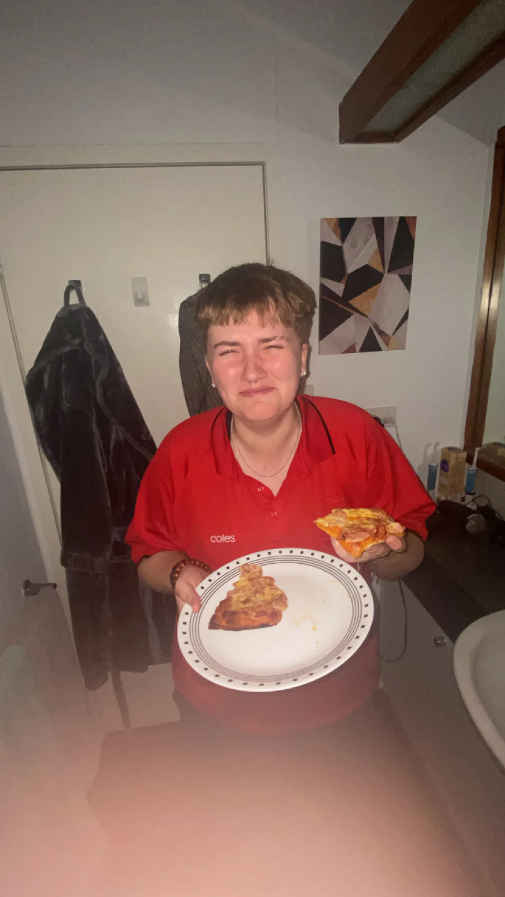 A person in a red shirt holding two slices of pizza